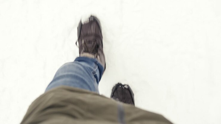 Anonymous Person Wearing Jacket And Winter Shoes Walking Carefully In Snow