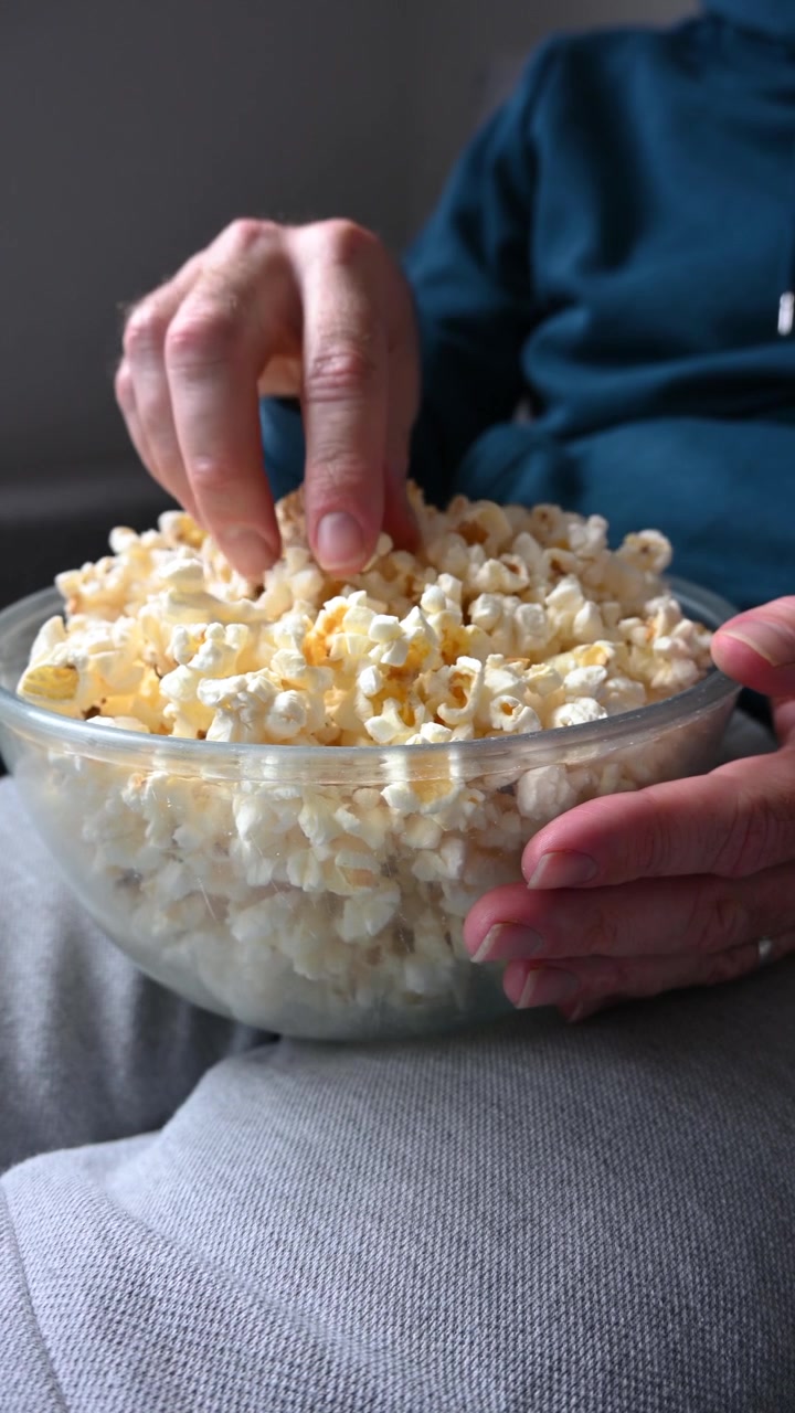 Uomo che mangia popcorn sul divano