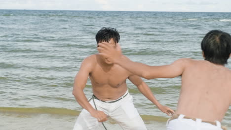 두 남자가 해변에서 카포에라를 춤추고 있다
