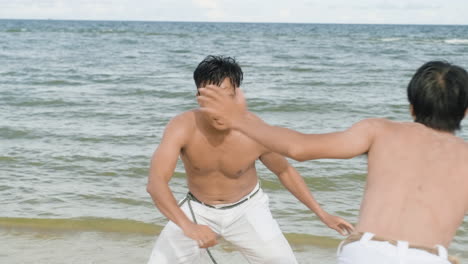 dos hombres bailando capoeira en la playa