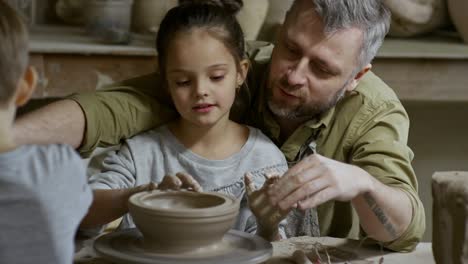 cinemagraph of father and daughter forming clay bowl