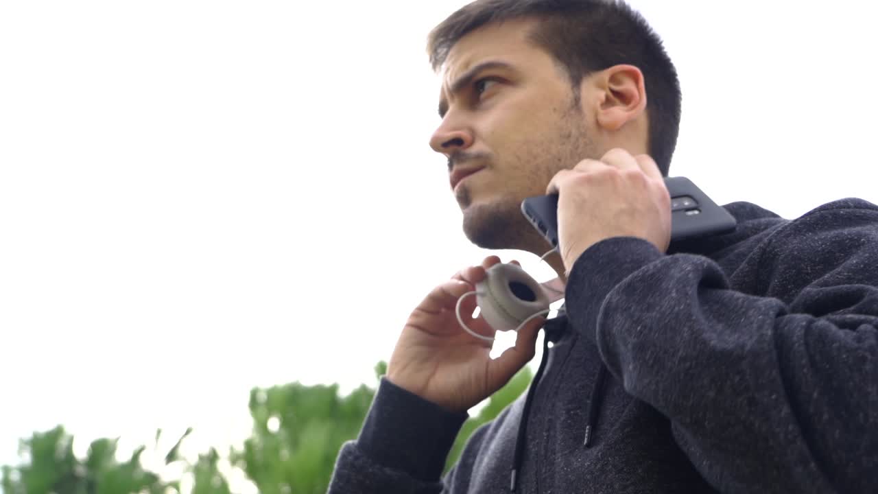 헬멧과 하얀 하늘이 있는 흰색 배경에 대해 모바일에 재생 목록을 넣는 남자