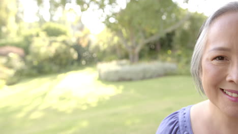 Smiling senior asian woman enjoying sunny day in garden, feeling happy and relaxed