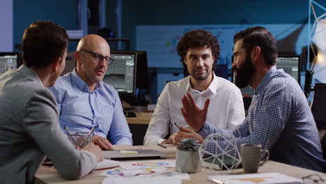 four businessmen sitting at the table and discussing their future plans in the office, then two of them shake hands