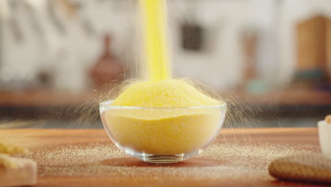 yellow cornmeal or polenta being poured into a clear glass bowl