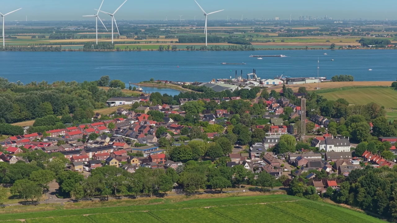 Splendida prospettiva aerea del villaggio olandese di Moerdijk, situato lungo il fiume Hollands Diep con turbine eoliche e navi da carico di passaggio