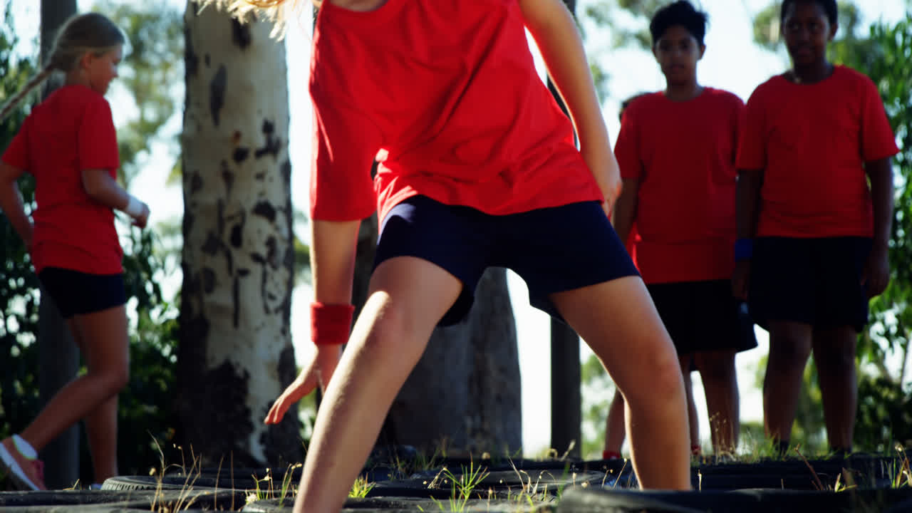 장애물 코스 훈련 중 타이어를 뛰어넘는 아이들