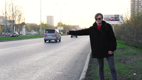 man hails a taxi on city street