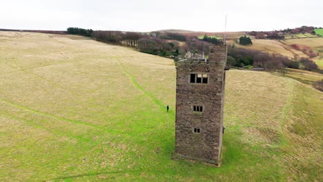 Old-derelict-castle,-monument,-disused-stone-tower,-with-people-walking-around-and-flying-a-drone