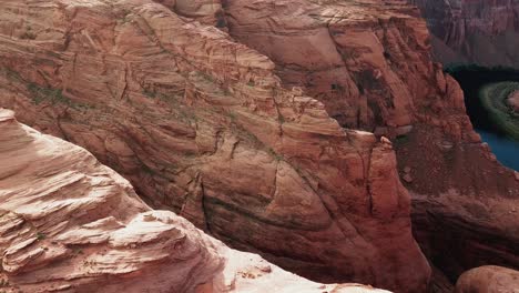 steep vertical sandstone canyon of colorado river and horseshoe bend meander in arizona desert, aerial view