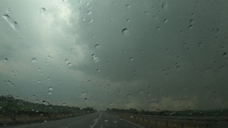 Regentropfen-Auf-Der-Windschutzscheibe-Des-Autos-Bei-Schwerem-Sommersturmregen,-Regenzeit-Auf-Der-Autobahn