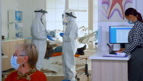 doctors in full virus protection uniform talking in surgery room