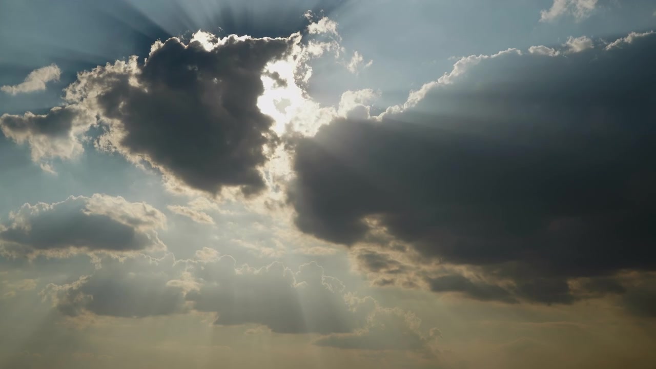 Raggi di sole che filtrano attraverso nuvole scure nel cielo.