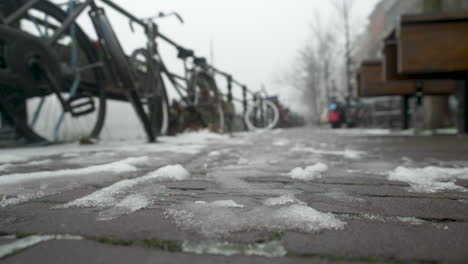 frozen ice on the streets of amsterdam on a misty day with a bicycle rack and bikes in the background