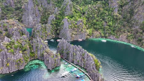jagged limestone cliffs around the twin lagoon in coron, palawan, philippines. - aerial pullback shot