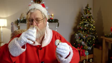 santa claus relajándose en una silla y comiendo dulces