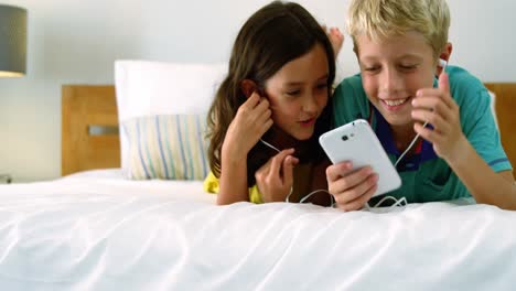 Siblings-using-mobile-phone-in-bedroom
