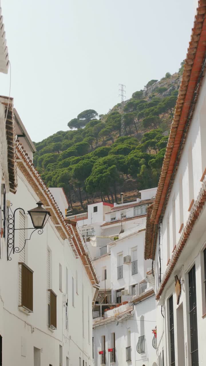 Slow motion POV shot walking between whitewashed Andalusian houses in Mijas Pueblo with hillside view