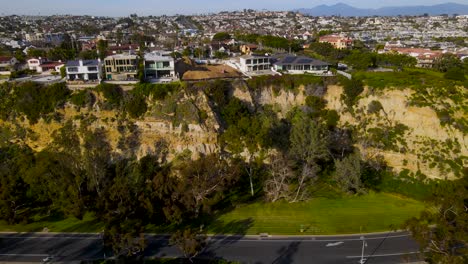 Stunning-luxury-homes-on-cliffs-above-tree-covered-roadway-on-sunny-day