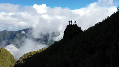 Drone-shot-of-3-people-standing-together,-watching-and-enjoying-the-view-over-Sao-Vicente-in-Monte-Trigo