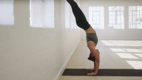 Mujer-De-Yoga-Saludable-Practicando-Handstand-Pose-Disfrutando-De-Un-Estilo-De-Vida-Fitness-Haciendo-Ejercicio-En-El-Estudio-Estirando-Un-Hermoso-Entrenamiento-Corporal-En-Una-Colchoneta-De-Ejercicios