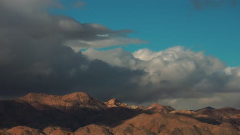 dark and ominous storm clouds forming and blowing over the mountainous peaks of the mojave desert borderland - time lapse