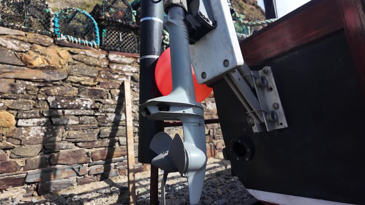 Industrial boat equipment beside a weathered stone wall, featuring a metal propeller, dock gear, and orange buoy