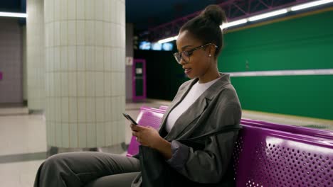 mujer usando el teléfono en una estación de metro