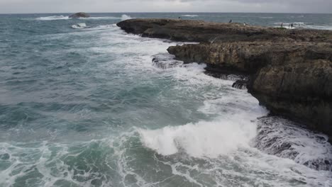 WAVES-SPLASHING-AGAINST-ROCK-POINT-IN-LAIE-HAWAII-OAHU-DRONE-ARIEL-SHOT