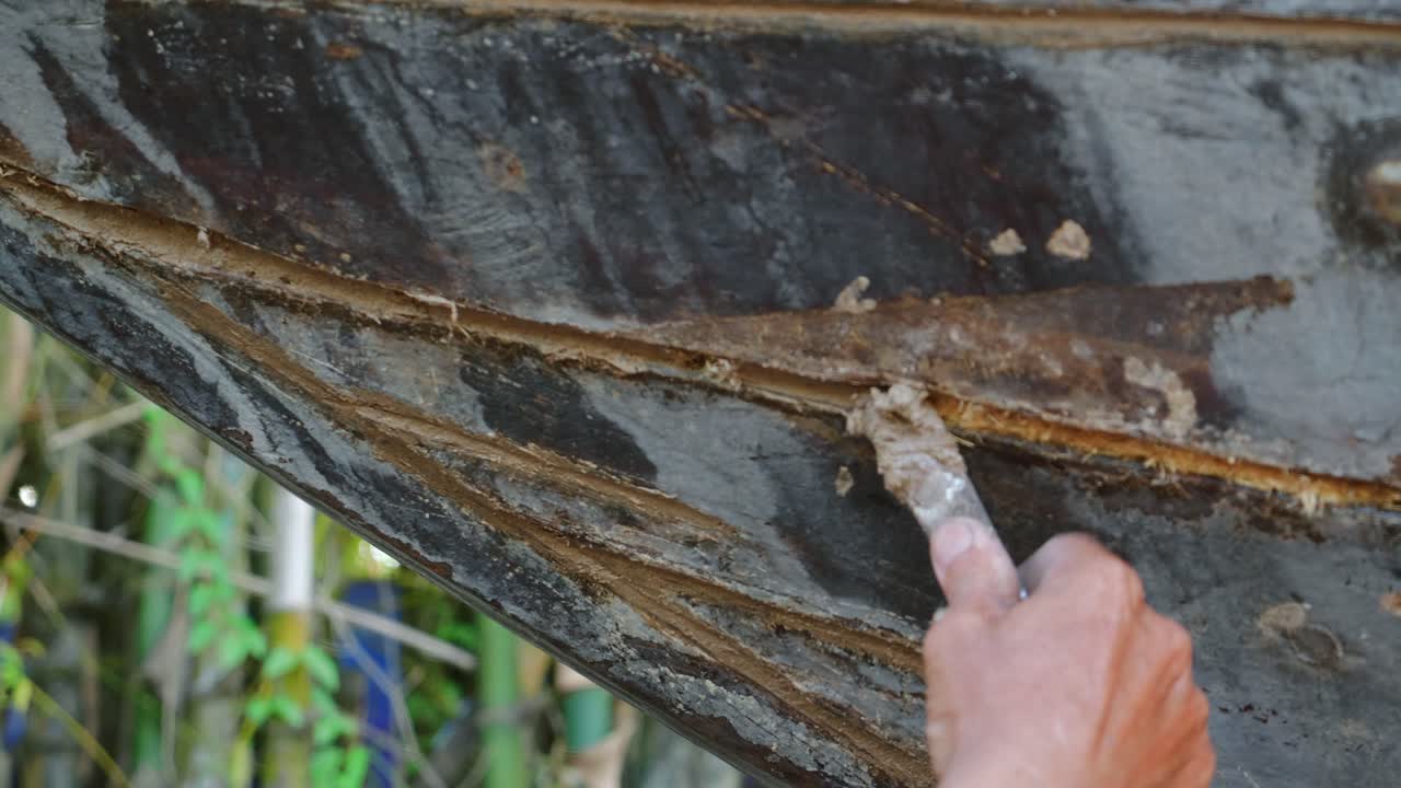 Una tradizionale barca in legno viene mantenuta aggiungendo cotone da calafataggio alle giunture