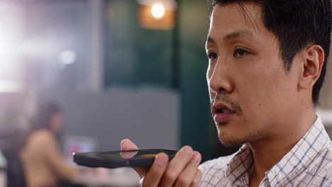 communicating in modern office, man speaking into smartphone
