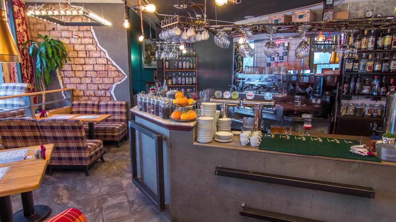 Timelapse interior kafe modern dengan konter, meja kayu, dan kursi, tanpa orang. Kafe ini memiliki bar teh dengan mesin kopi dan gelas untuk minuman