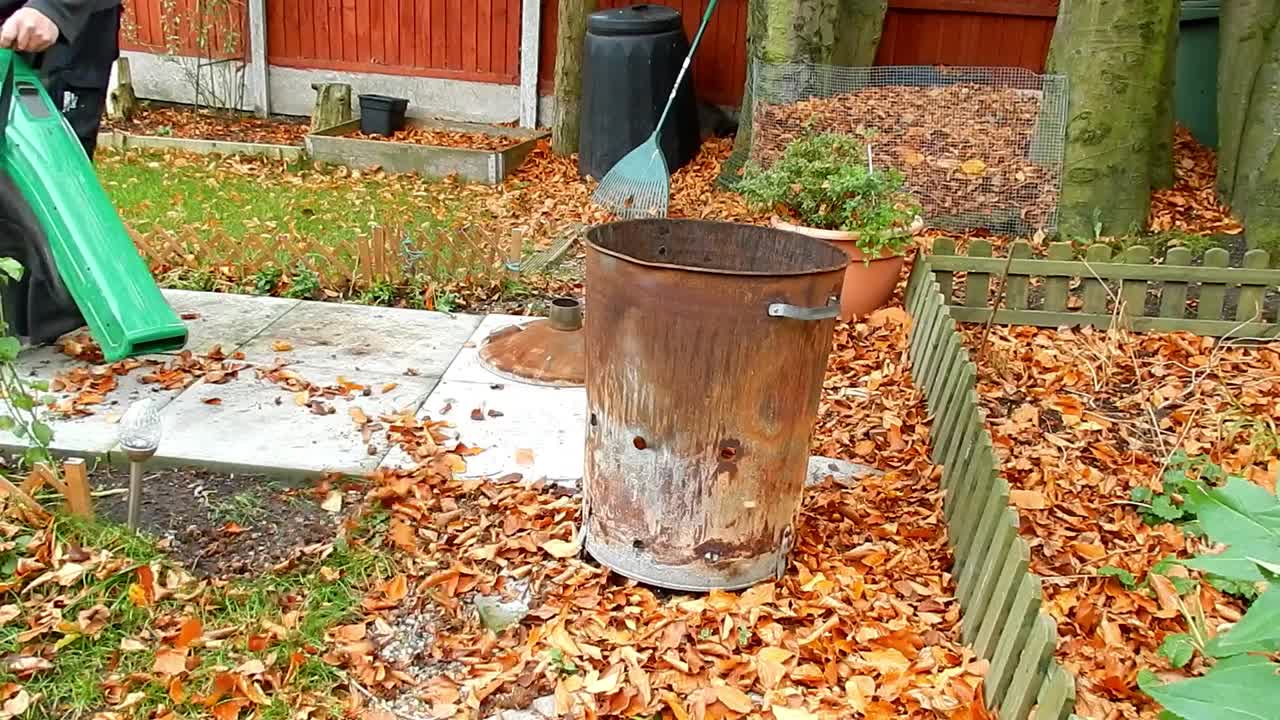 잎 송풍기 진공 청소기로 바람이 부는 정원에서 잎을 치우다