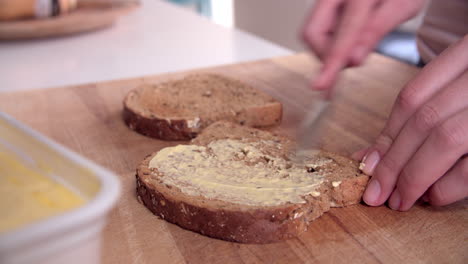 Persona-Untando-Mantequilla-Sobre-Una-Rebanada-De-Pan-Tostado