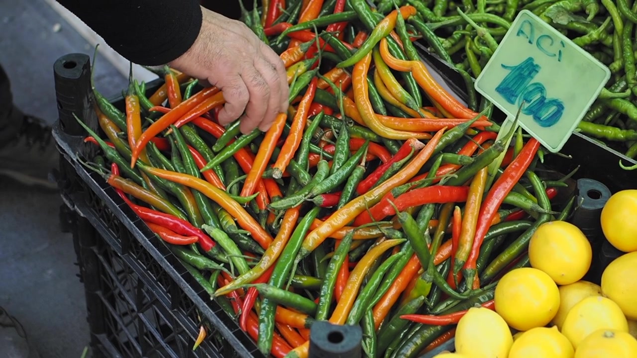 Cliente che sceglie peperoncini freschi in una bancarella del mercato locale