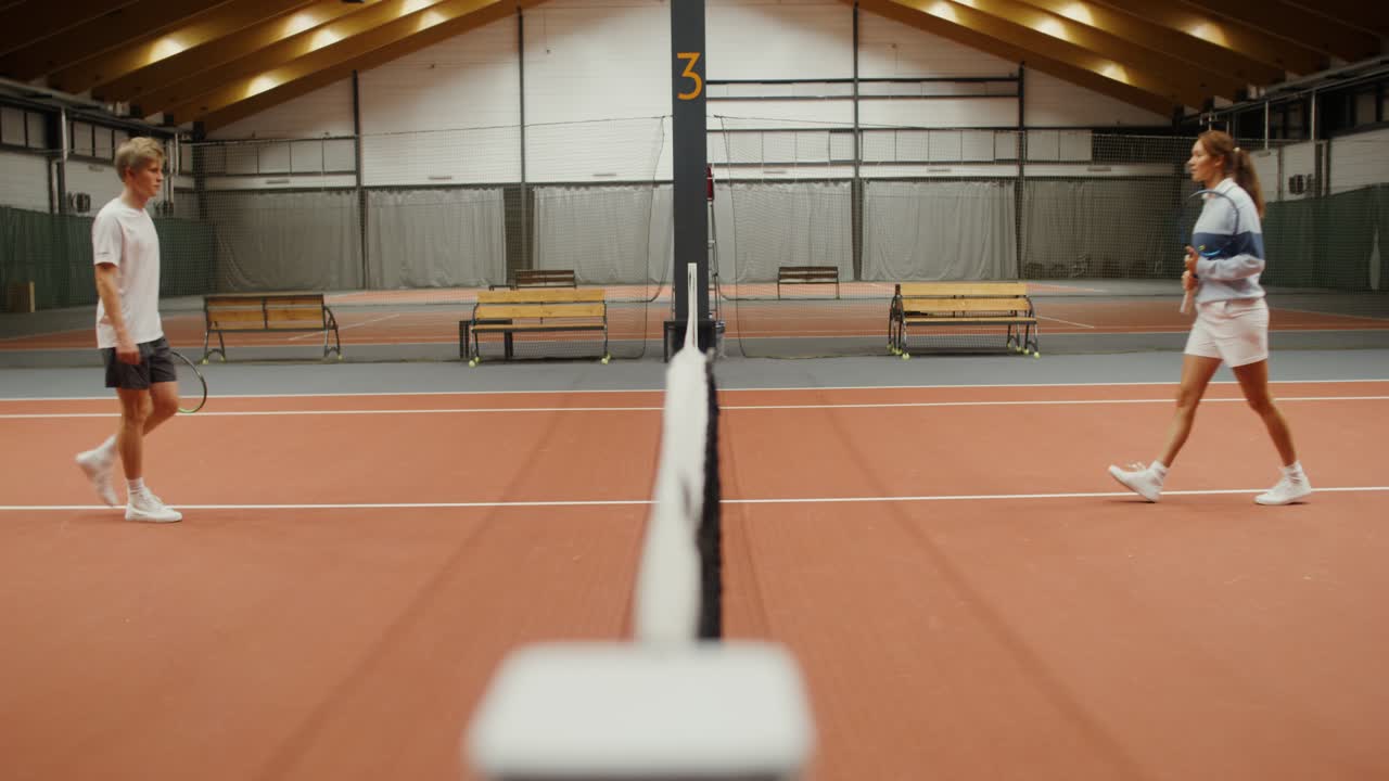 una pareja jugando al tenis en una cancha cubierta.