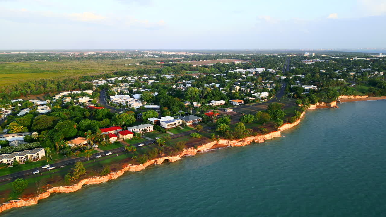 Aerial pull back of a small coastal town revealing cityscape in the distance