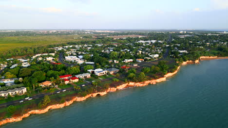 Aerial-pull-back-of-a-small-coastal-town-revealing-cityscape-in-the-distance