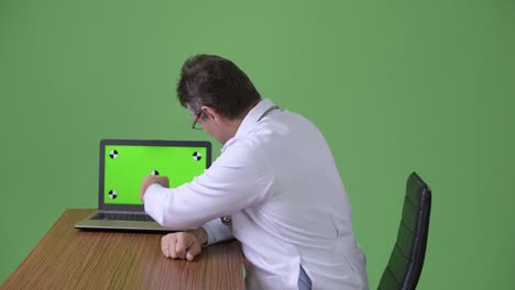 hombre maduro y guapo médico contra fondo verde