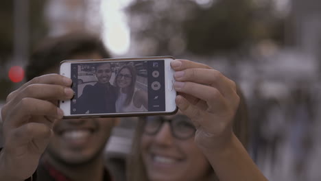 smiling young couple taking selfie with smartphone