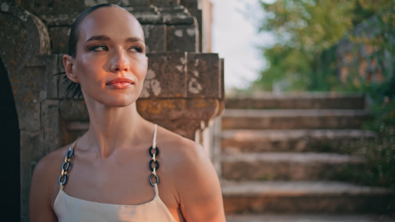 무관심한 여성은 오래된 건물 계단에서 빛을 즐기고 있습니다. 편안한 소녀