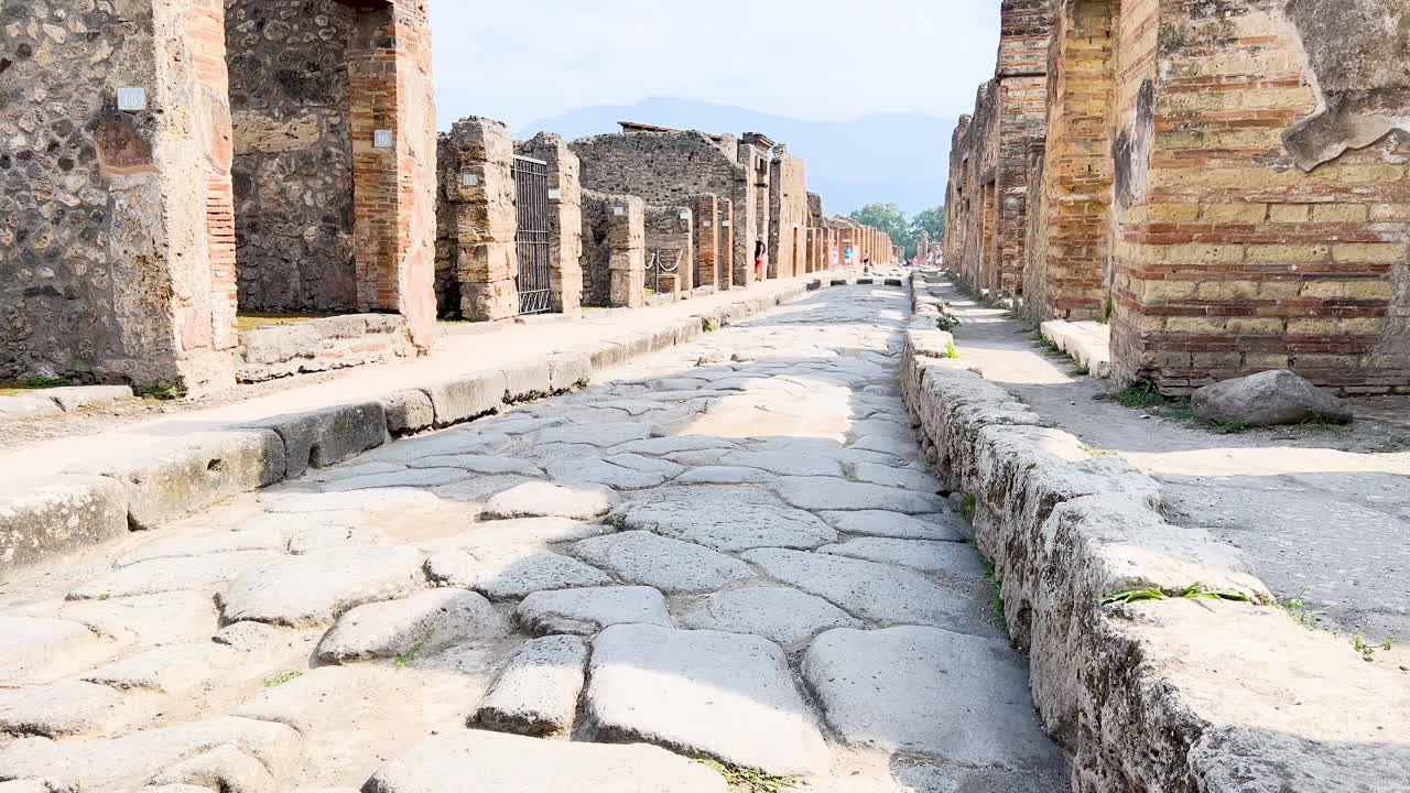 antiguas ruinas de una calle romana, con columnas y pavimento de piedra, bajo un cielo soleado - pompeya