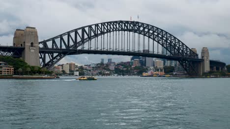 a boat passes beneath the iconic sydney harbour bridge, highlighting the massive steel structure as it spans the harbor, connecting the vibrant city skyline.