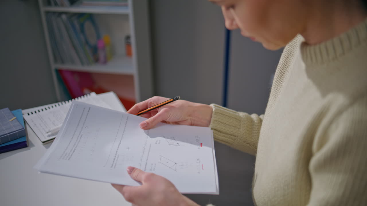 Attentive educator checking algebra test at class room closeup. Woman working