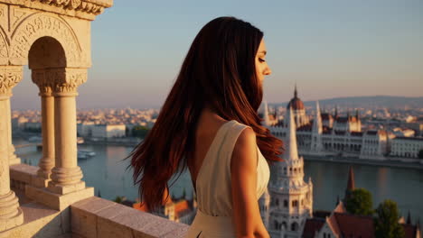 elegant woman overlooking budapest cityscape from a historic balcony at sunset