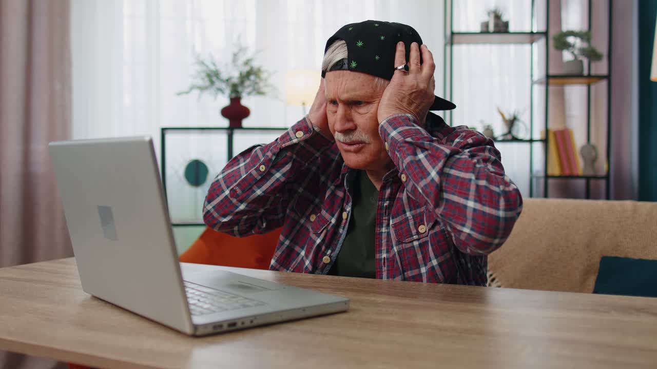 Stressed upset senior grandfather man working on laptop computer received bad loss news at home