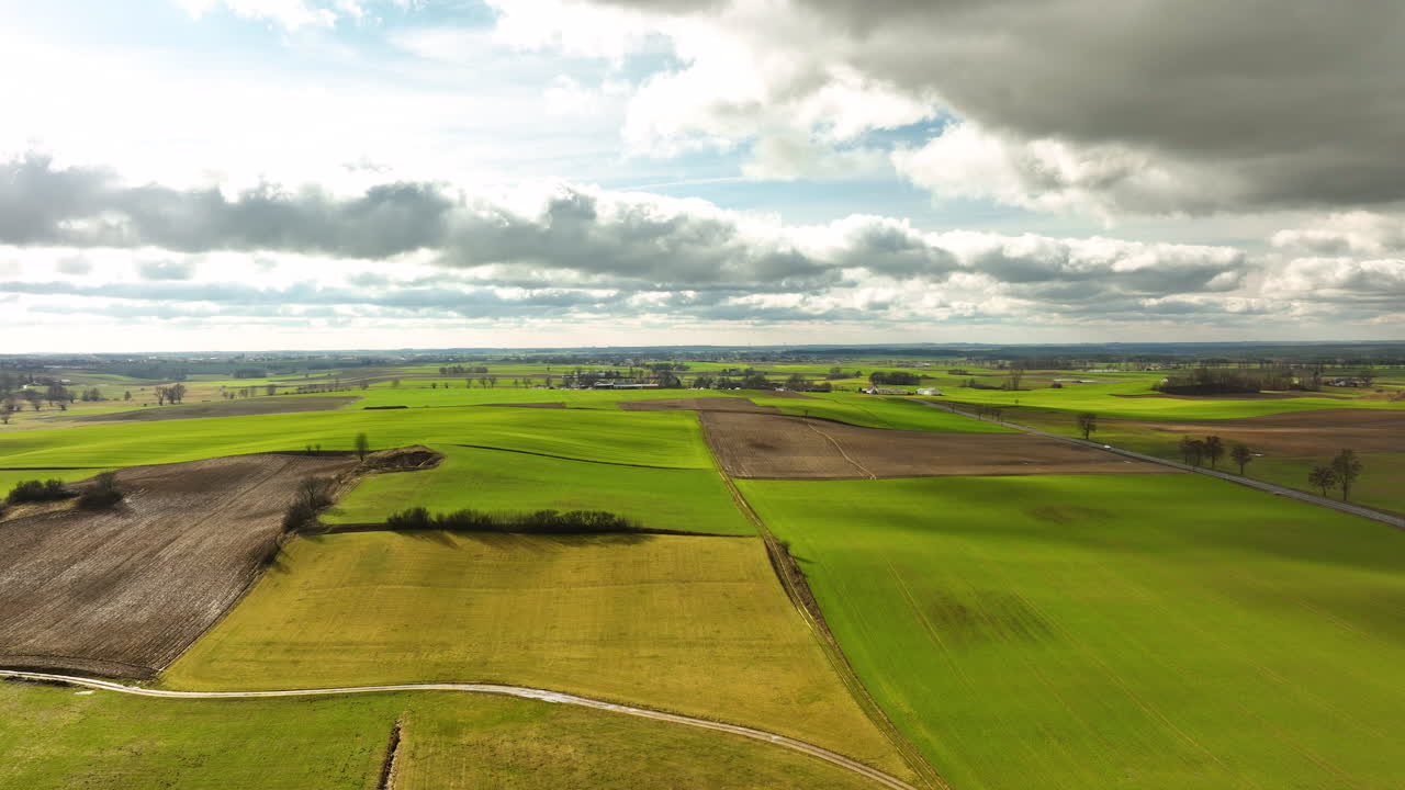 Aerial - Expansive agricultural fields under a cloudy sky