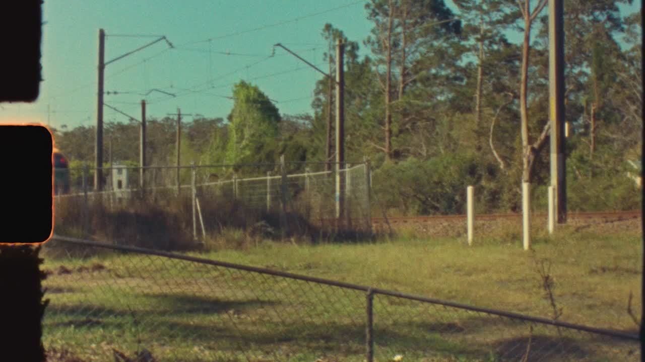 super 8 película vintage de vagón de tren expreso de cercanías en las vías del ferrocarril en la ciudad suburbana de narara costa central de australia transporte viaje fugas de luz