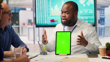 Adviser-shows-green-screen-on-a-tablet-to-middle-aged-people-in-modern-office