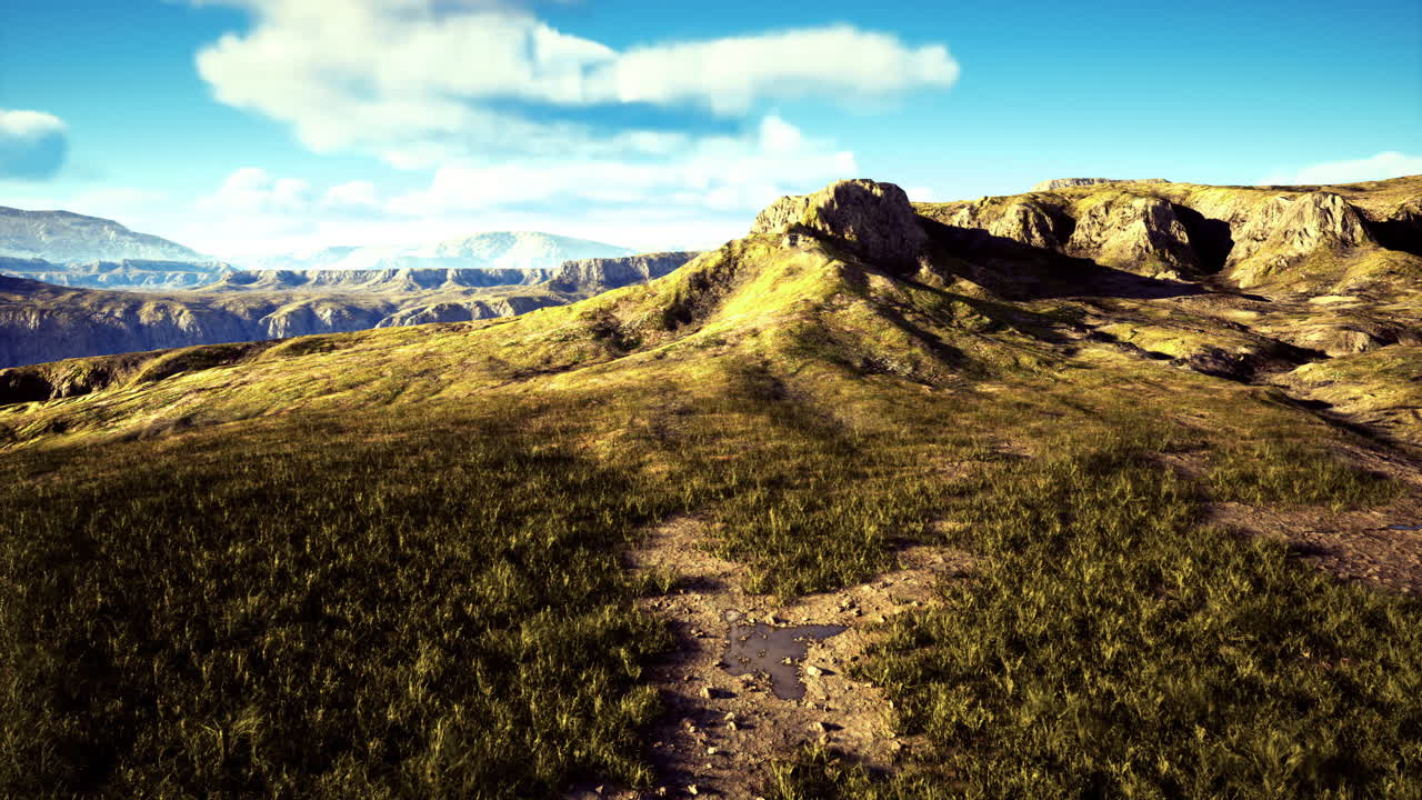 Vast green landscape with rolling hills and distant mountains under clear sky